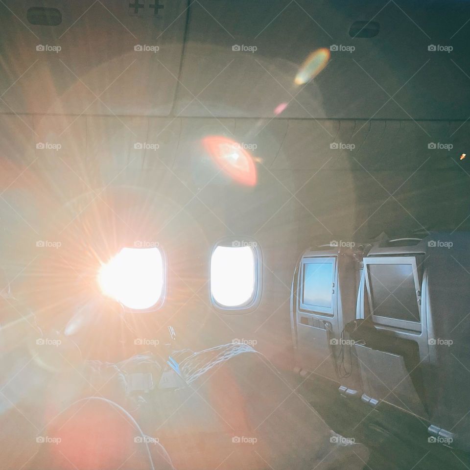 Sun comes in through airplane window, morning sun on a long flight, high up in the clouds, good morning on the plane, windows on airplanes