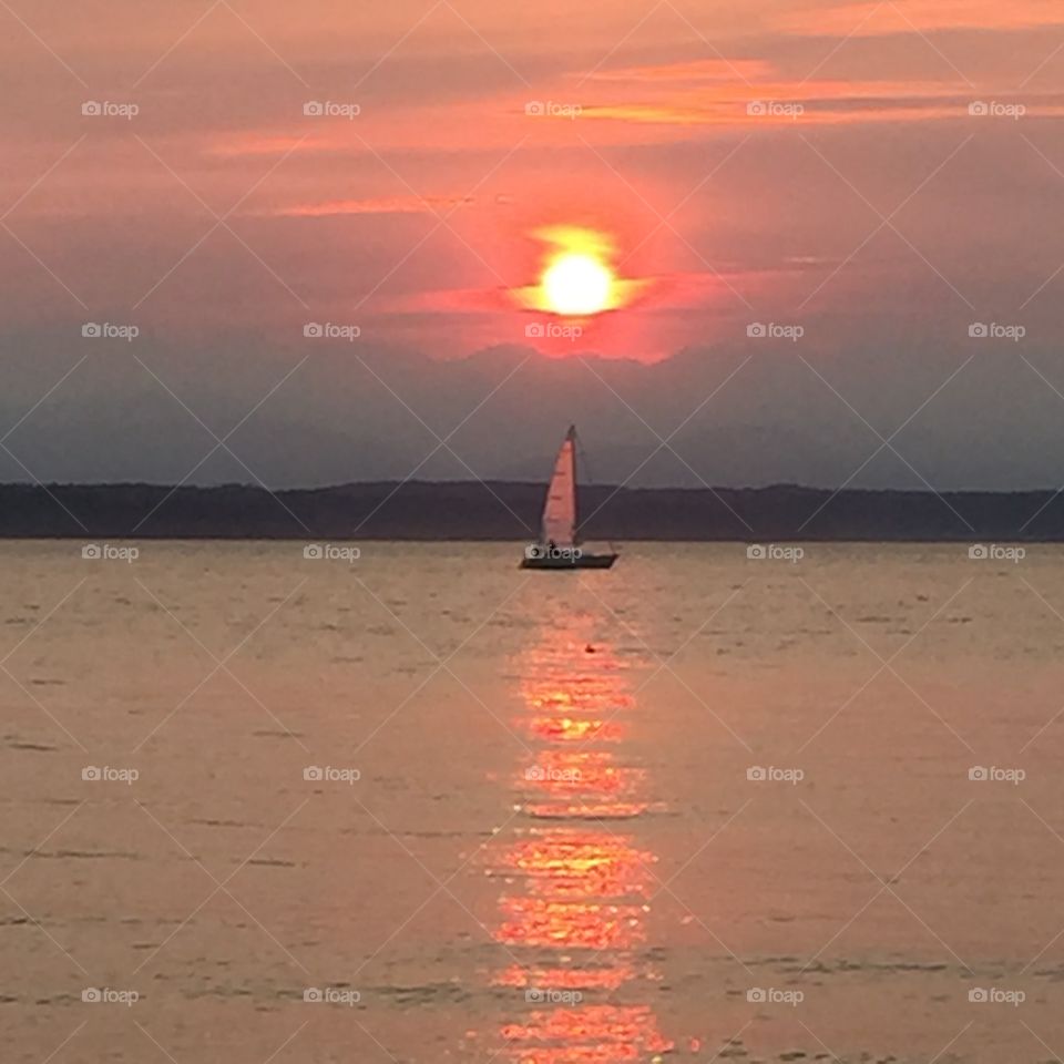 Sunset & sail. Fiery Seattle sunset  due to wildfires with sailboat in reflection 