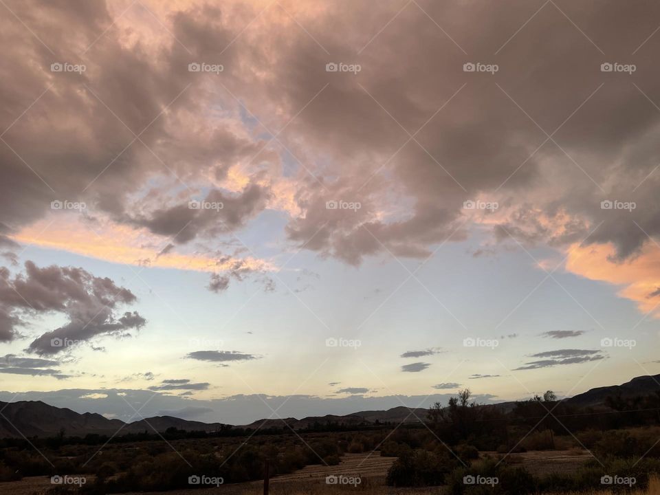 A blue sky with pink clouds floating above several mountains. 