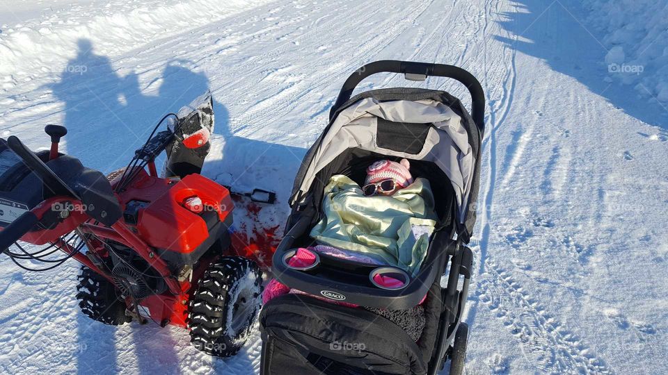 momma had to snow blow the driveway, baby watched from under a pile of blankets from inside the garage door. cozy inn my stroller piled high with blankets. sun shades for a sunny winter day