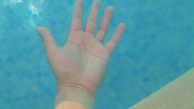Hand into blue water.