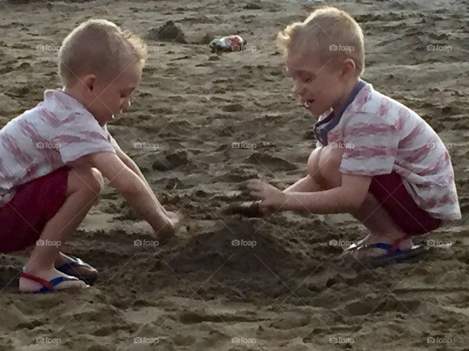 Summer evening. Twin boys having fun on beach 