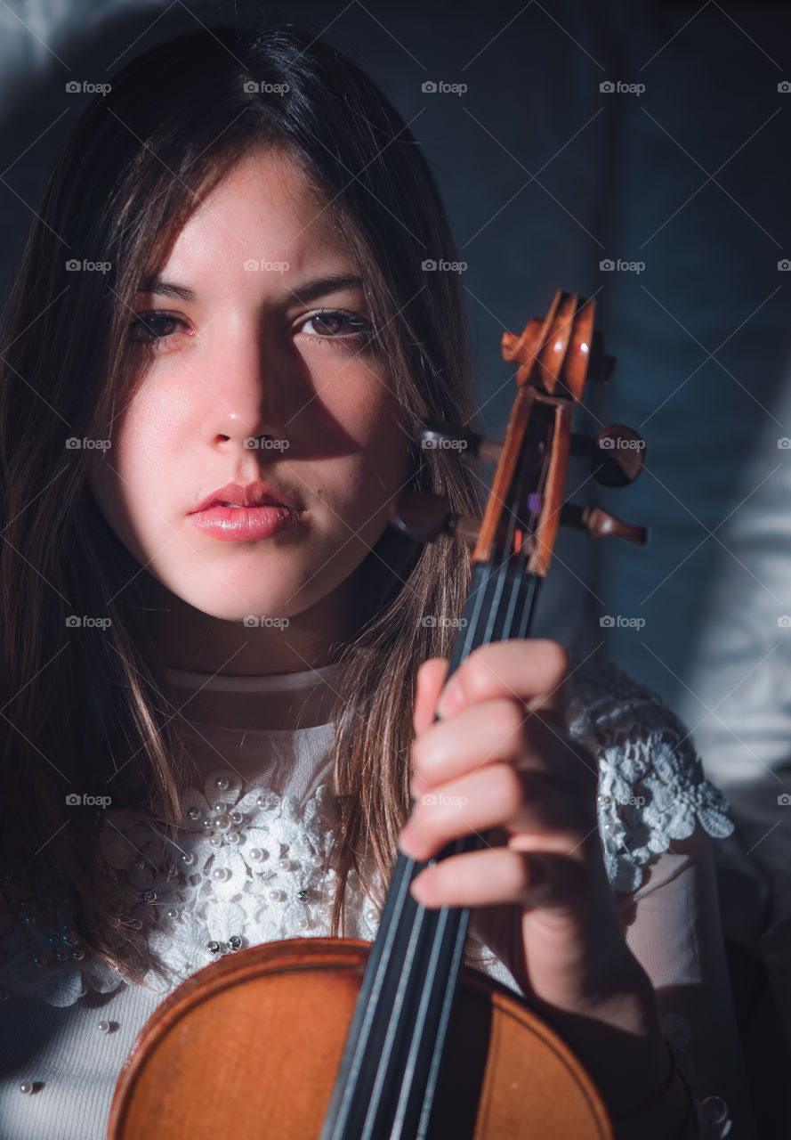 Girl holding a violin in the house