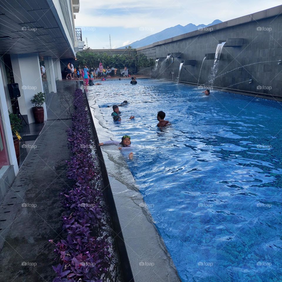 a swimming pool with lots of children on the weekend