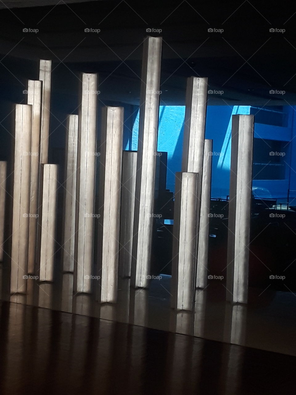 estructuras rectangulares de metal paradas, en piso de madera y acabados con fondo de luz azul