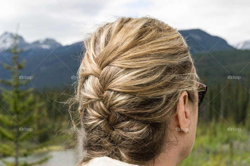 French braid hair style, woman facing toward Rocky Mountain scene