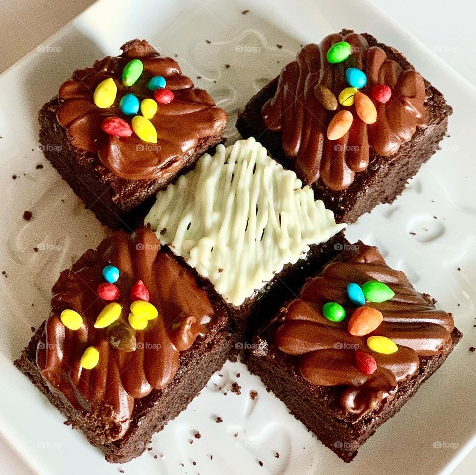 Home baked brownies in white chocolate drizzle and M&Ms sprinkles 