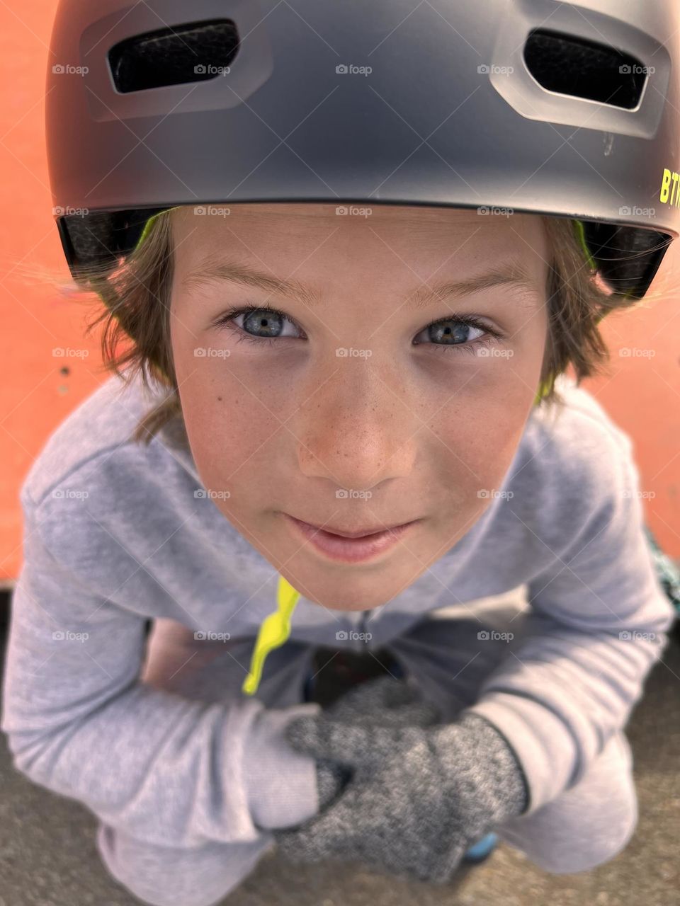 a handsome boy of eight years old, in a helmet, the child is tired and sat down to rest, the boy rides a scooter. Portrait 