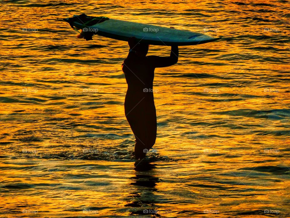 Woman entering the ocean with surfboard in Half Moon Bay, California
