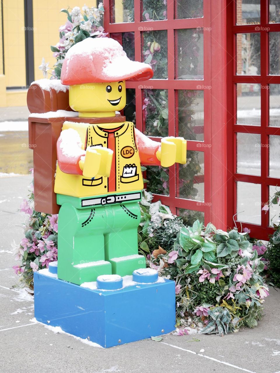 A Lego man stands patiently by a phone booth, waiting to make an important call. 