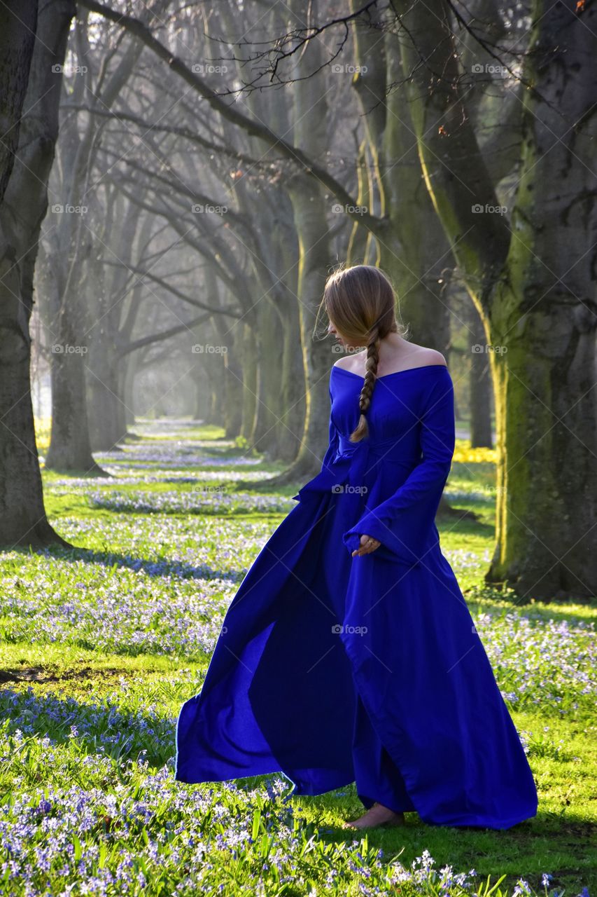 woman in blue dress in spring blooming alley in gdynia, poland