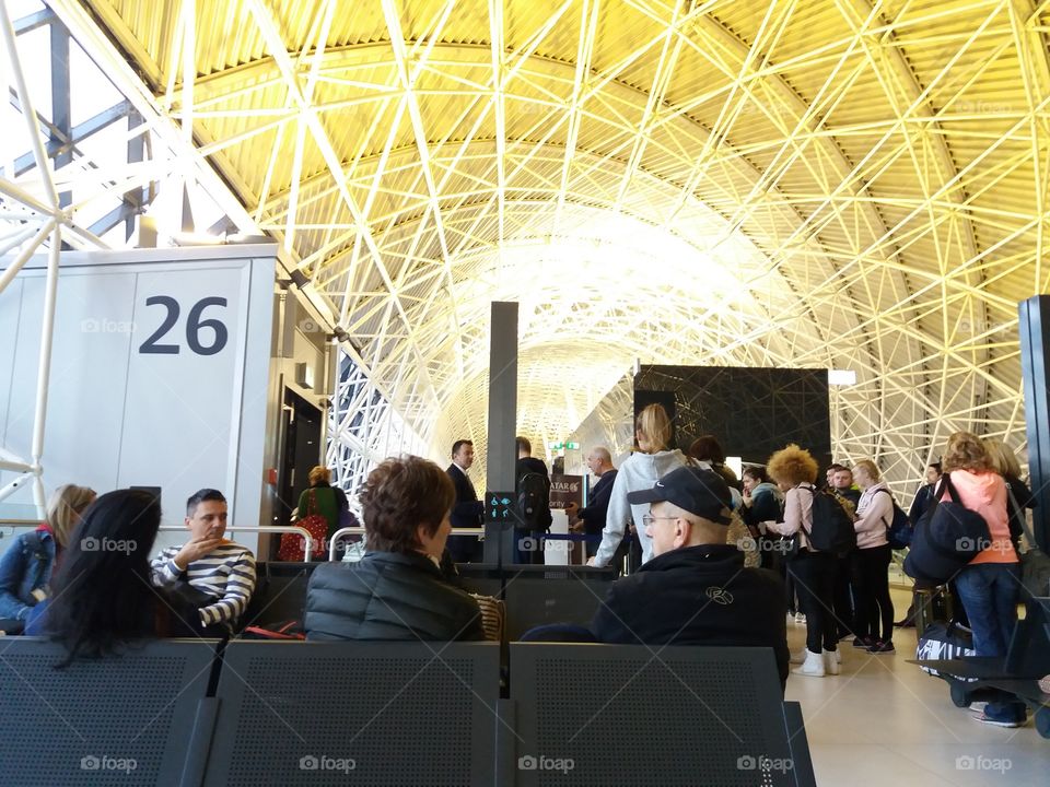 People waiting them flights at the airport with a amazing roof structure