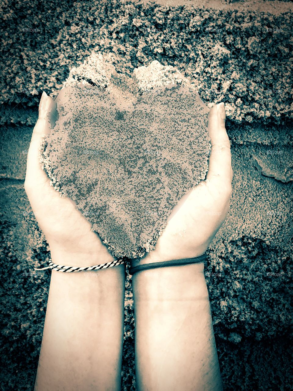 hands holding sand heart
