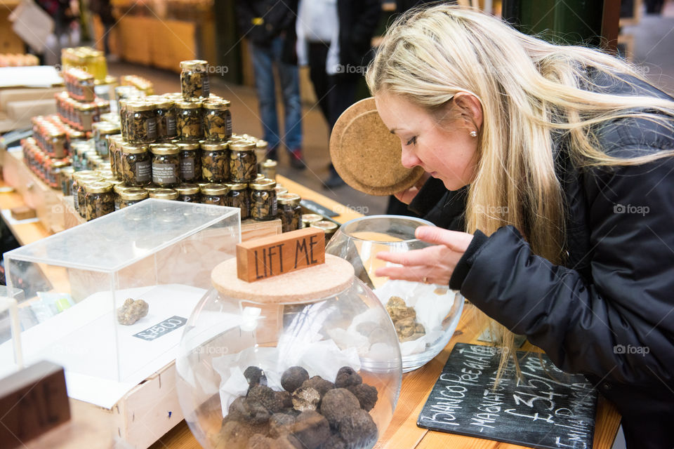 Young woman smells the exclusive mushroom Truffle at the food market Borough Market in London.  