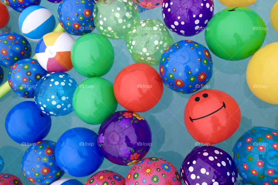 Bright Colorful balls with smiley face on one red ball in pool