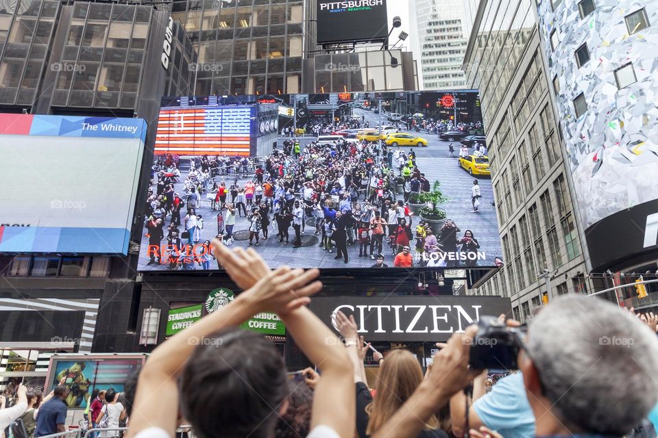 Crowd cheering up in front of huge digital screen in New York