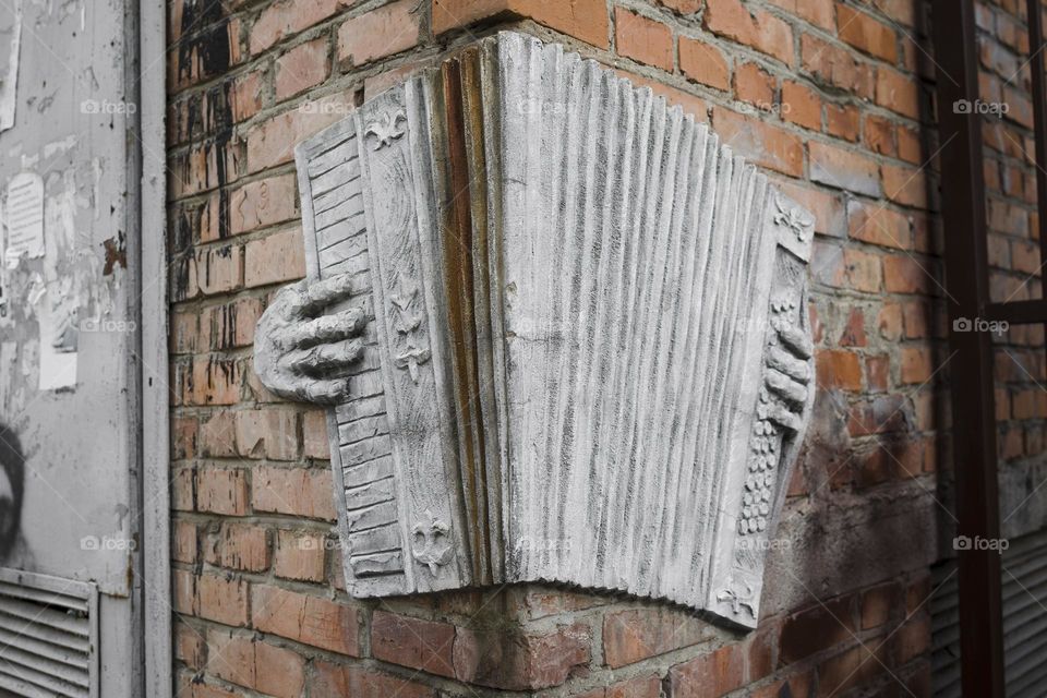 accordion sculpture on brick wall