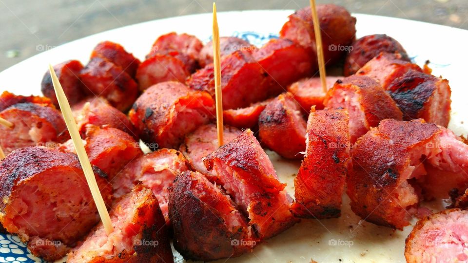 Porção de linguiça Toscana frita, num prato com palitos.