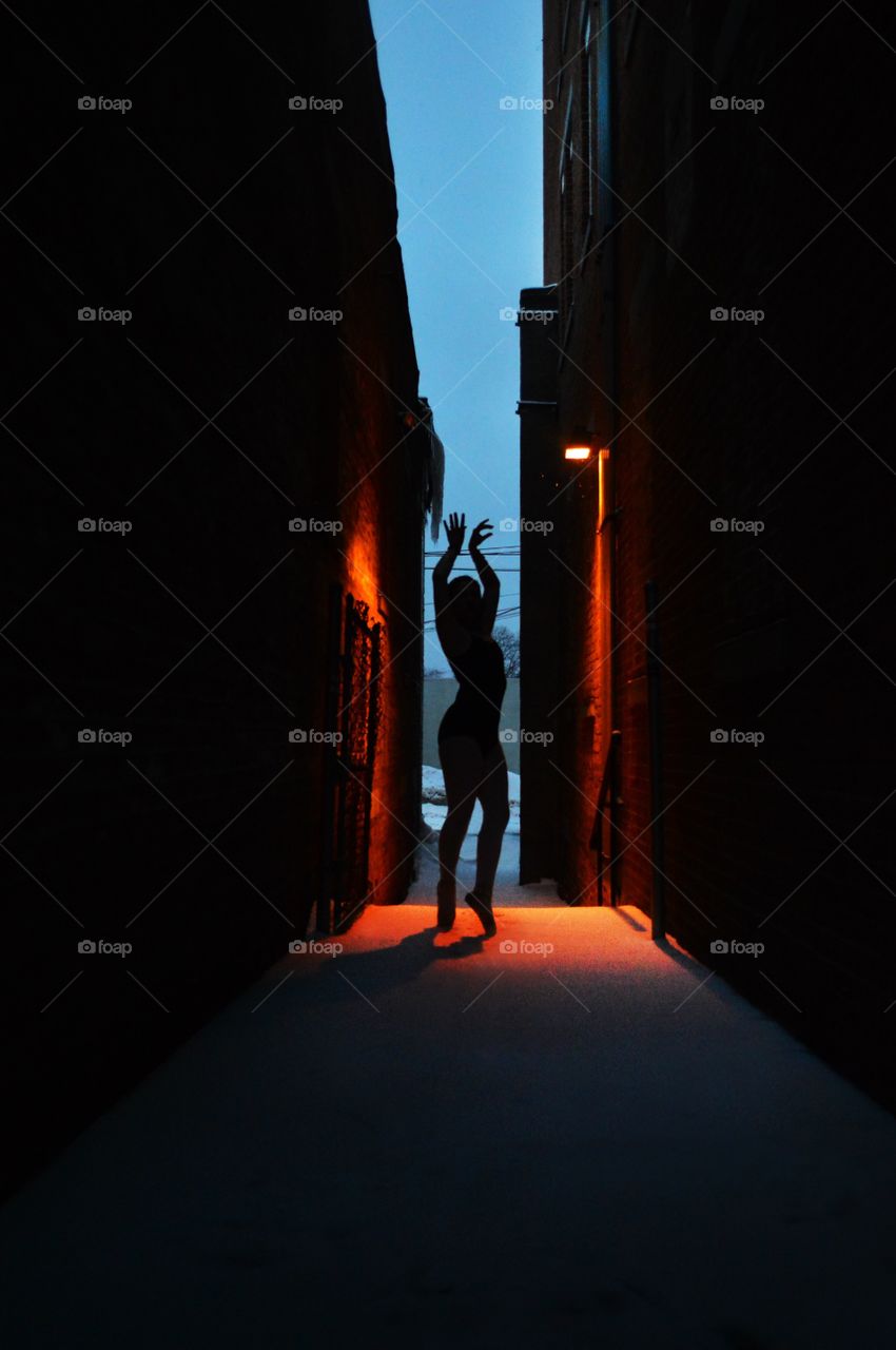 A dancer poses in the middle of an alley way 