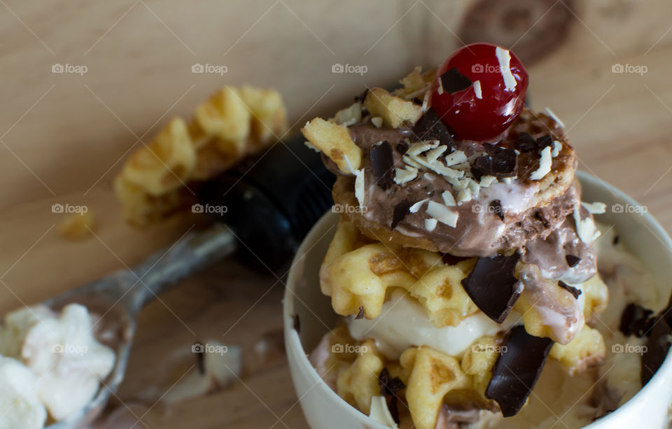 Decadent stack of Belgian waffles and ice cream sandwich garnished with cherry and chocolate, And Dutch caramel syrup "Stroopwafle" traditional gourmet waffles on wood table with ice cream scoop