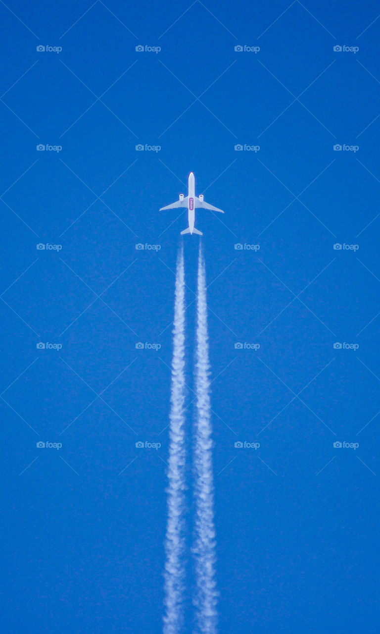 Airplane emitting vapor trail in clear blue sky details