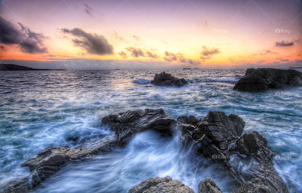Breaking Waves. Waves crash over hard rocks in an ocean scene at sunrise.