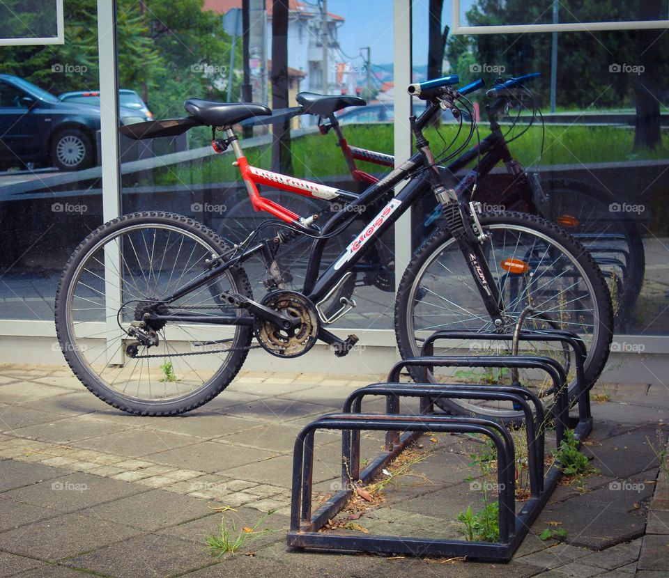 One lonely bicycle locked  in the front of the market with the reflection in the glass.