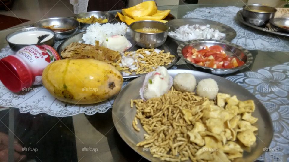 Indian mega meal with nankeen, fruits, rice, pulses, sweets, salad, paratha, pickle.