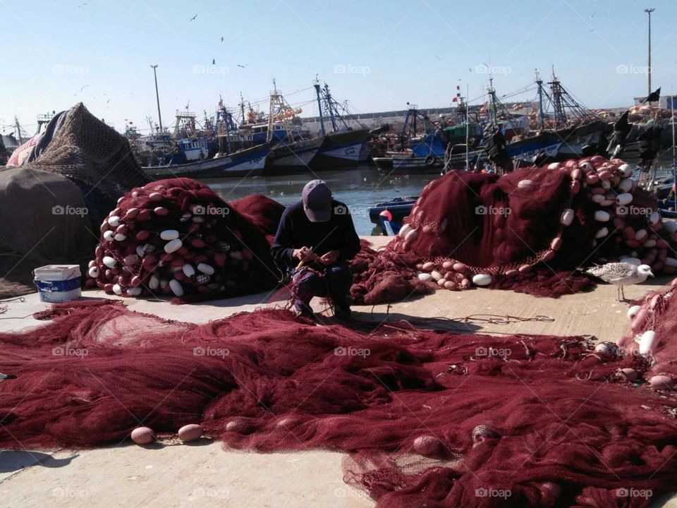 The fisherman and his fishing nets at essaouira harbour in morocco.