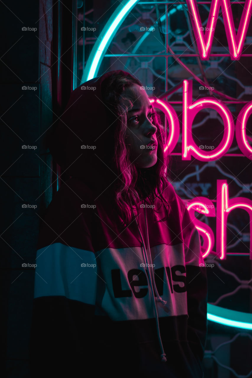 Girl with a hoodie in the neon lights.