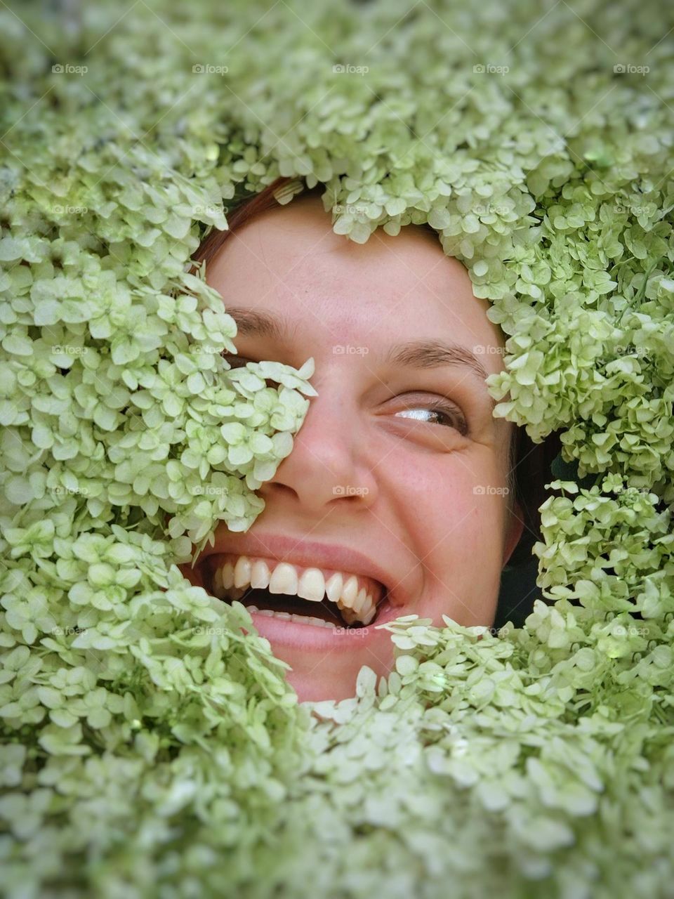 portrait of a happy and smiling girl among a bouquet of flowers from her garden