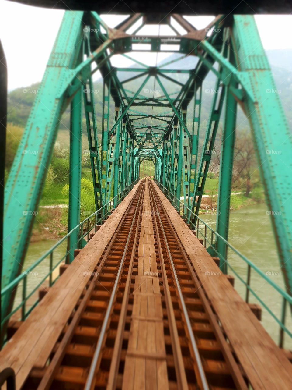 A view from the window of the last passenger wagon to the railway green bridge on the river of Bosna.