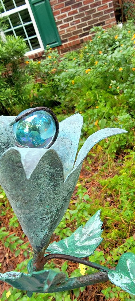 yard ornament reflecting home, flowers and trees