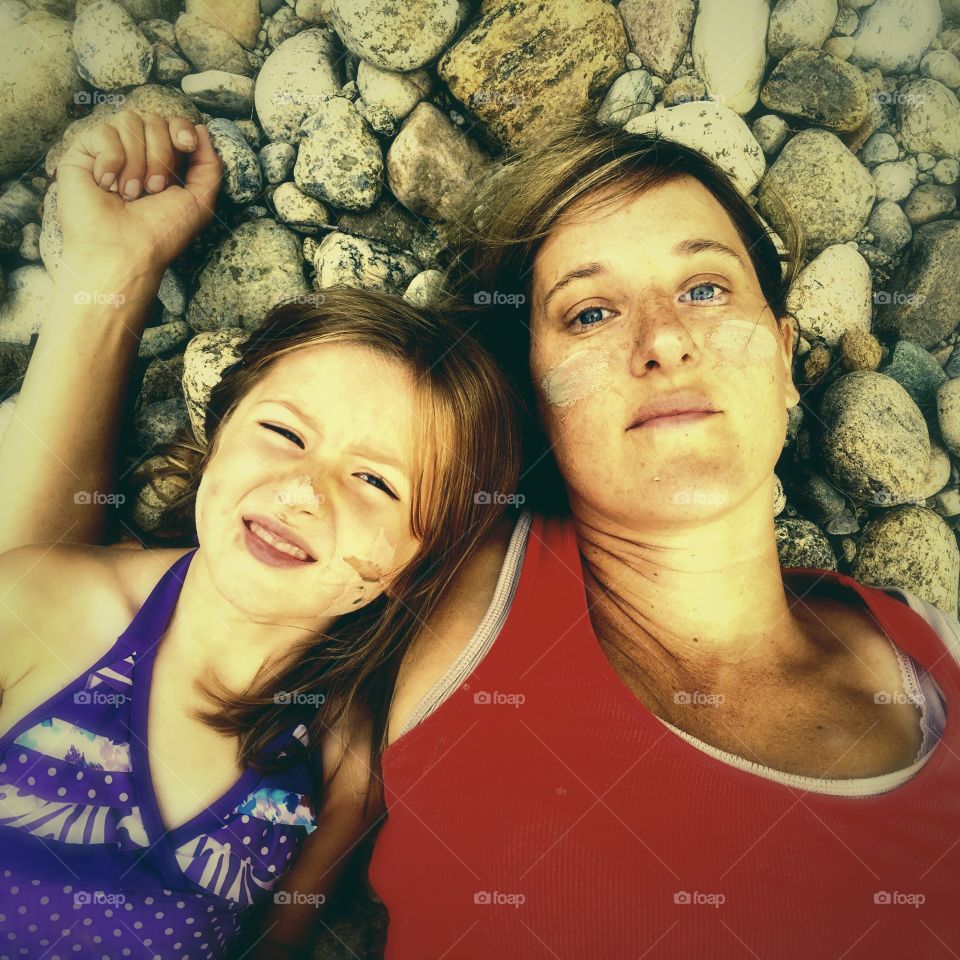 Mother and daughter lying on pebble stone