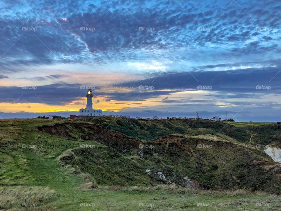 The sun sets behind Flamborough head lighthouse in the picturesque setting of flamborough, UK. 