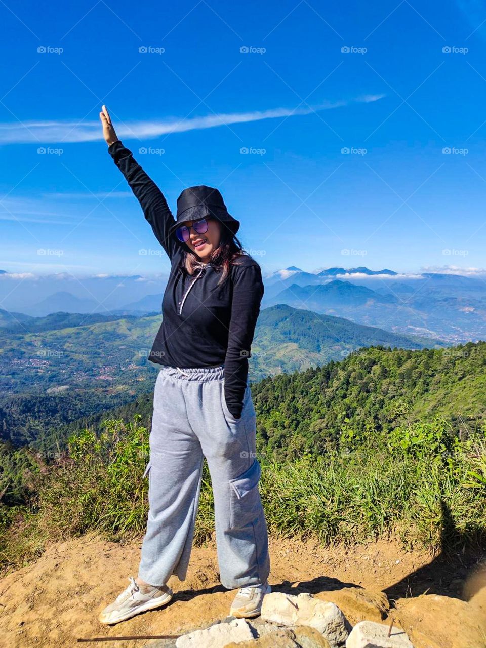 Full length of woman standing on mountain against blue sky