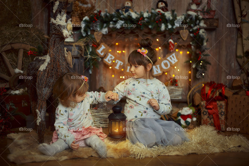 Little sisters near fireplace at Christmas Eve 