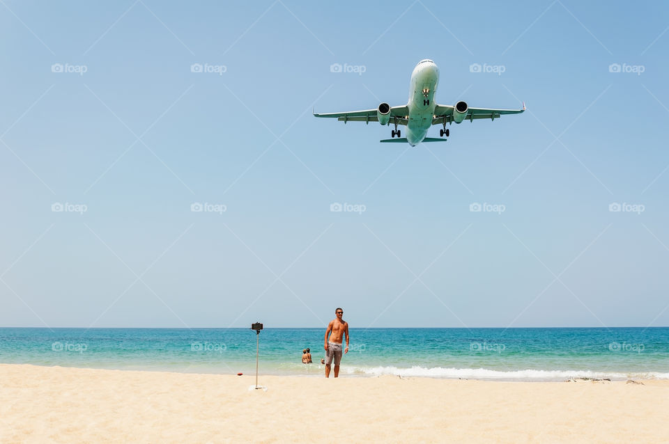 Summer and travel. Unseen Thailand, Some people relax on the white sand beach with blue sea and airplane come down to land