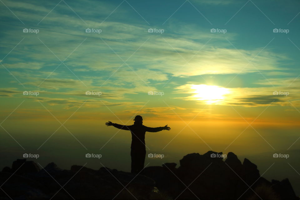 Silhouette of a woman with outstretched arms at sunset