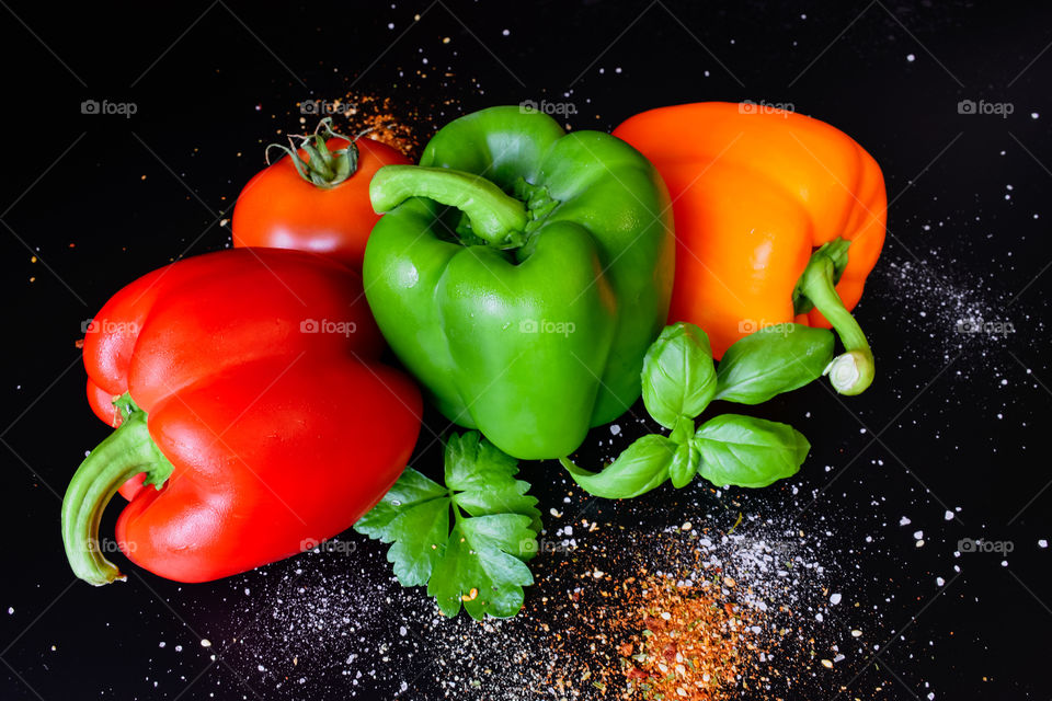 Tricolore paprika and tomatoes, basil and parsley in black background 