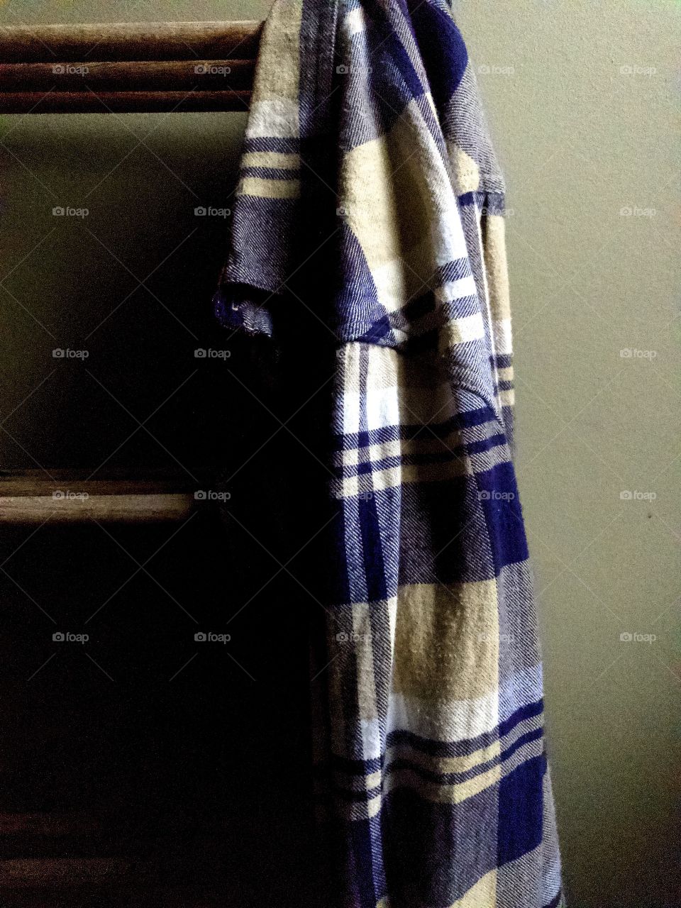 Closeup of blue plaid shirt hanging on wooden clothes rack 