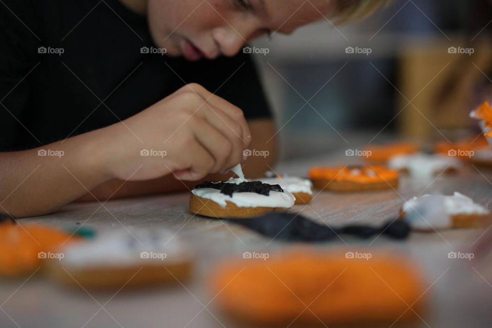 A seven year old child makes handmade cookies for Halloween.