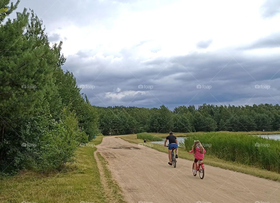 family riding on a bikes on a countryside road lake shore beautiful summer landscape