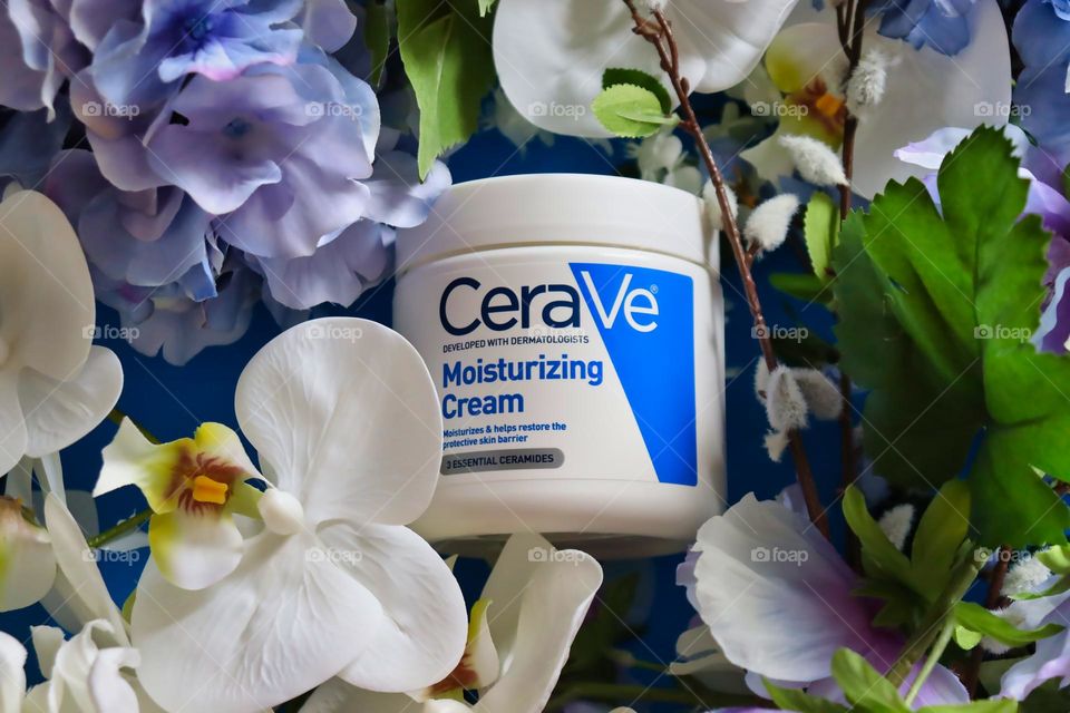 Cerave Moisturizing Cream on blue background with flowers. 