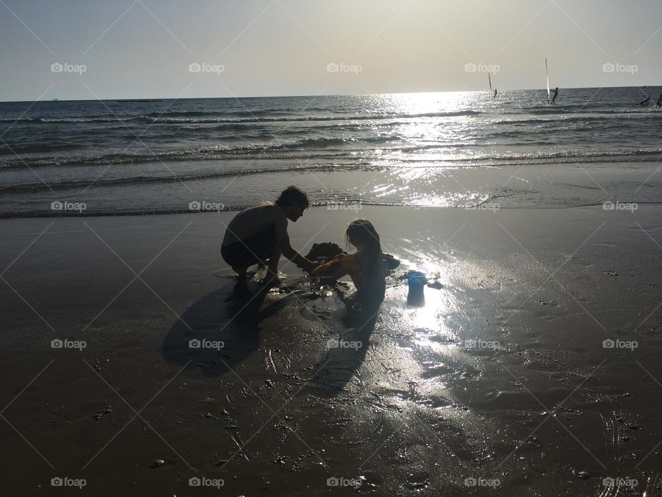 Father and girl playing on the beach sunset time