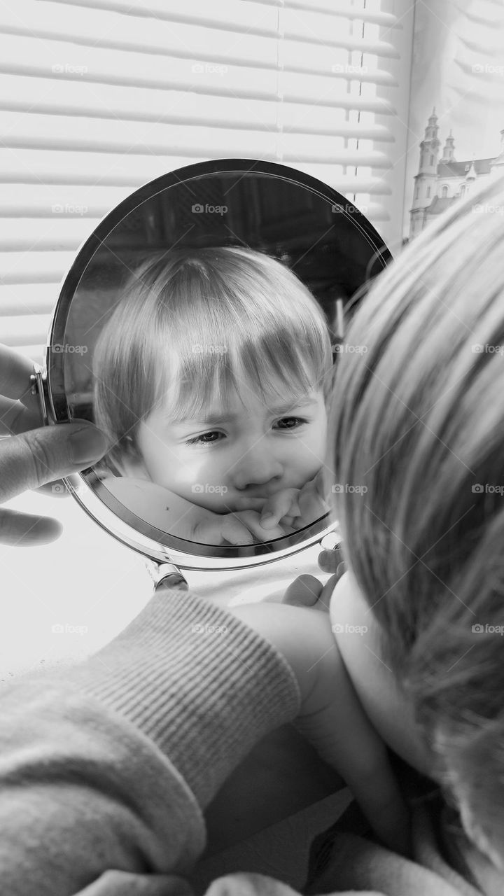 black and white photo of a child looking in the mirror