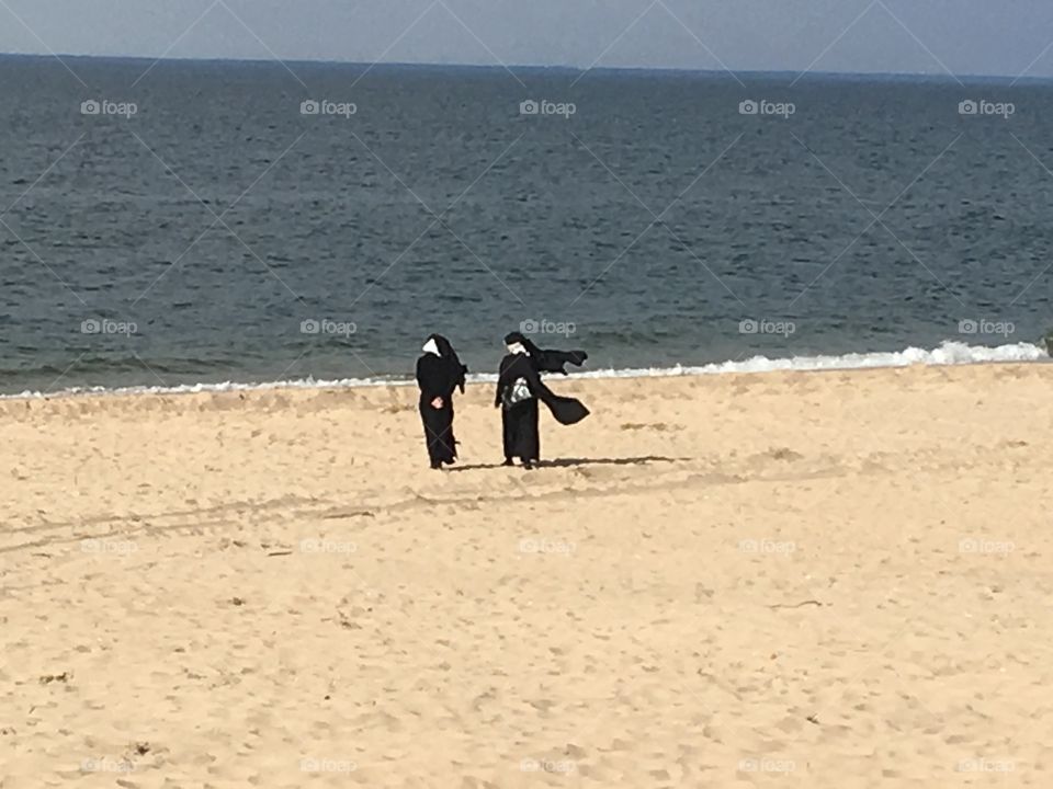 Two nuns walking on the beach on a beautiful Spring day.