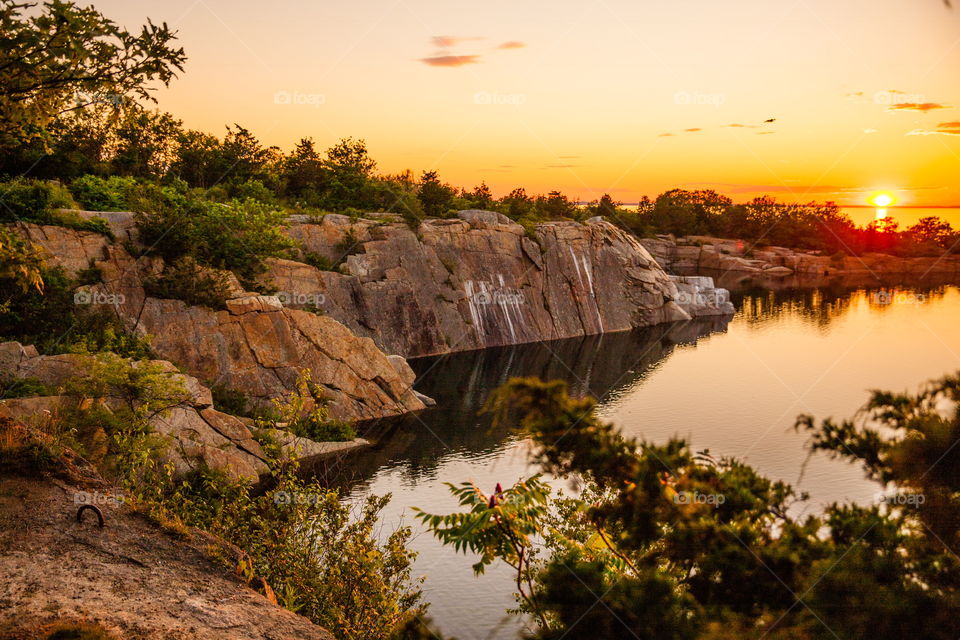 The sun setting over a quarry in New England with the Atlantic Ocean behind it. 