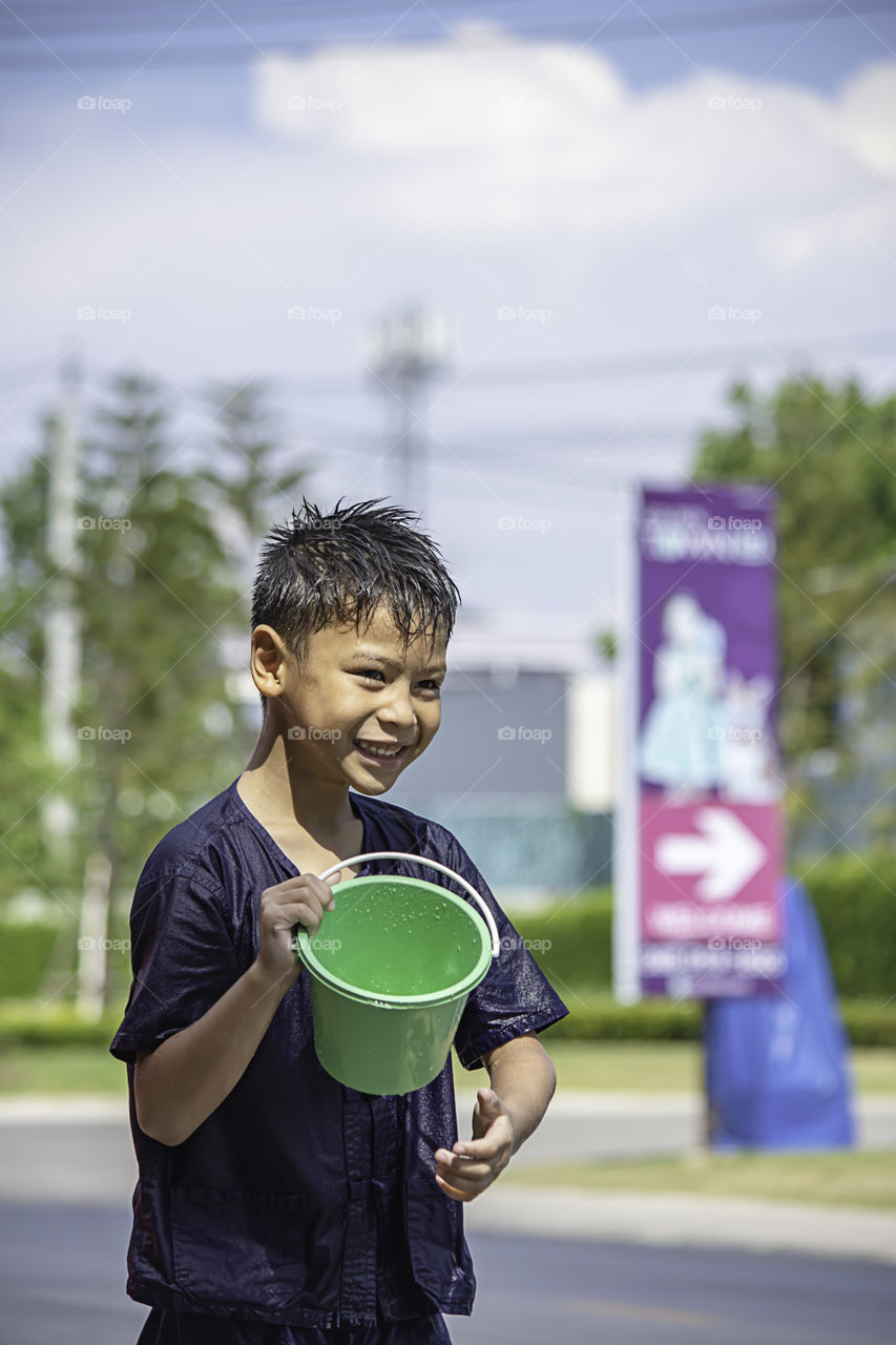 Asian boy holding Plastic bucket play Songkran festival or Thai new year in Thailand.