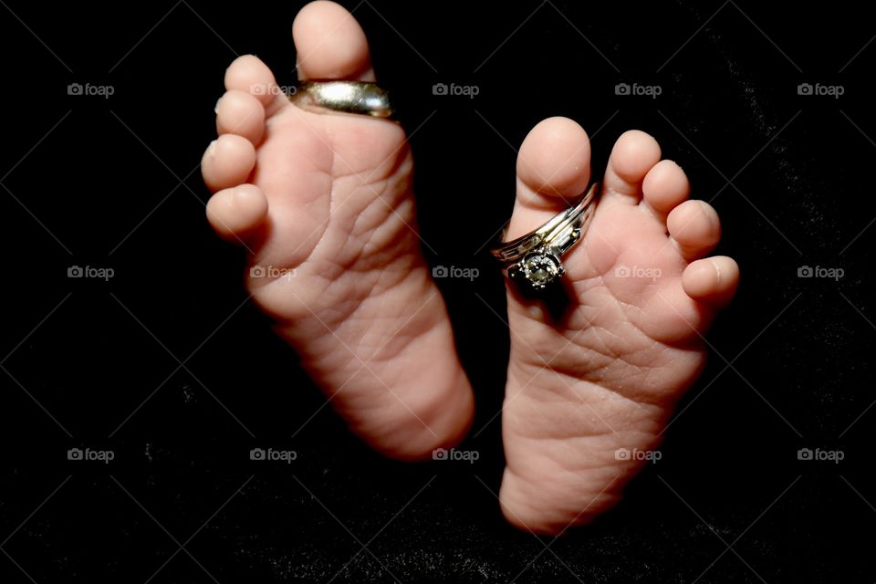 Infant’s feet with wedding rings on his toes 